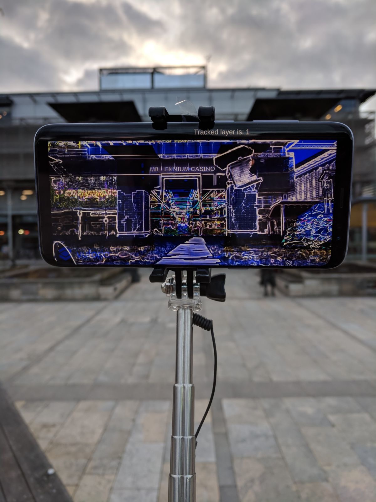 image of mobile phone on selfie stick showing AR rendering of Millennium Square in Bristol