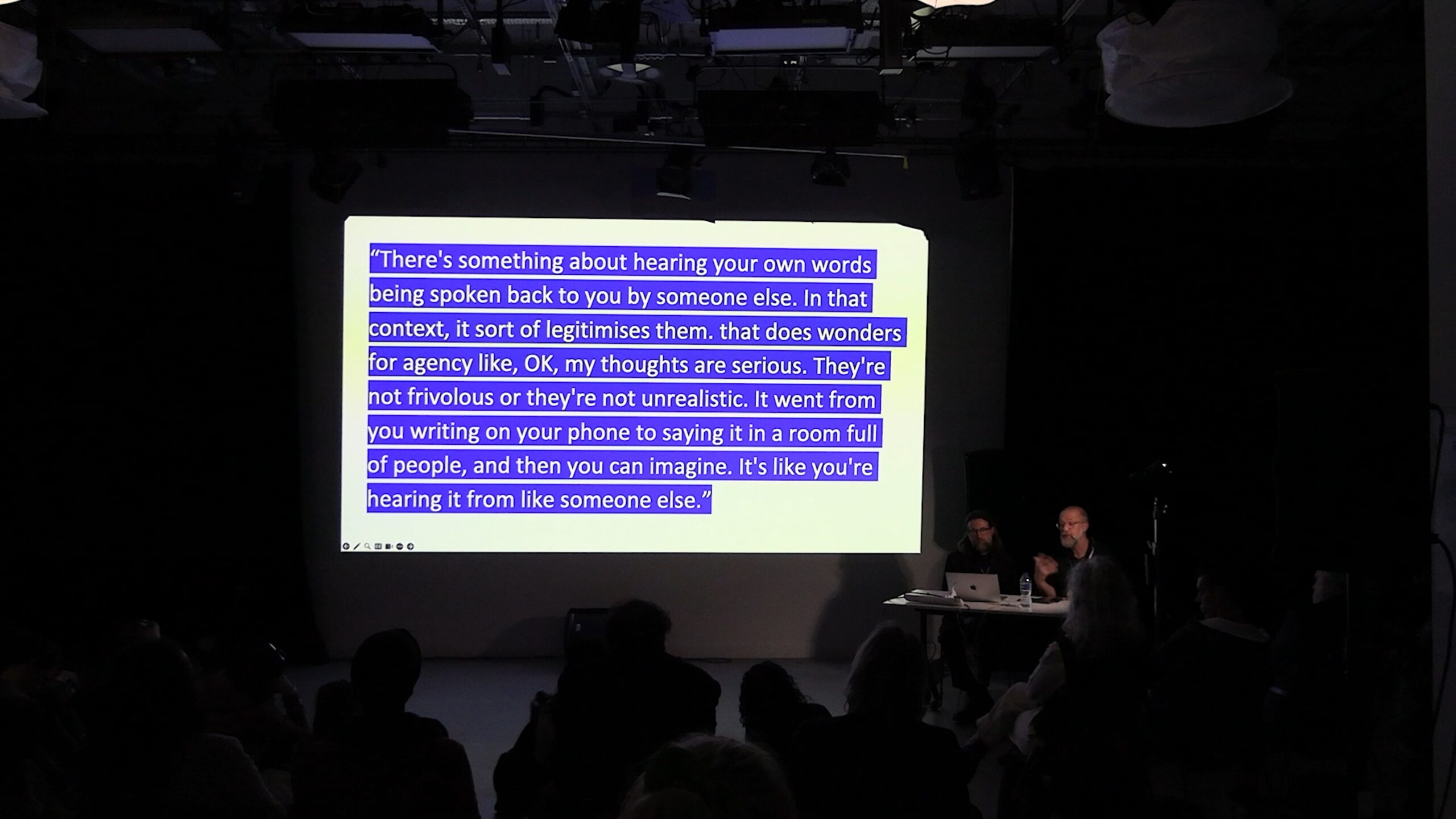 image of a large projection in a room. The projection is of text documenting a participant experience.